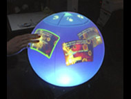 The sperical multitouch display is a homebrew internally projected image on a hollow polycarbonate sphere.  The multi-touch function is done with infrared (IR) lighting and camera.  A toolkit is underway for simple content delivery and interactivity (the prototype works with Flash).